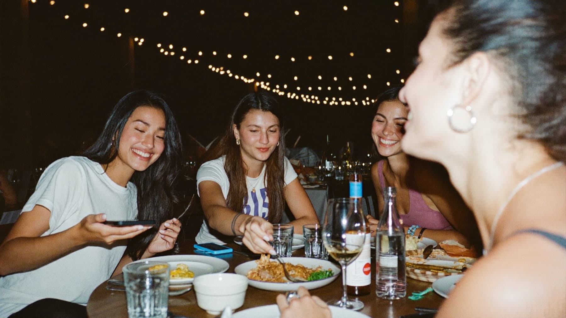 Friends enjoying the end of dinner under string lights