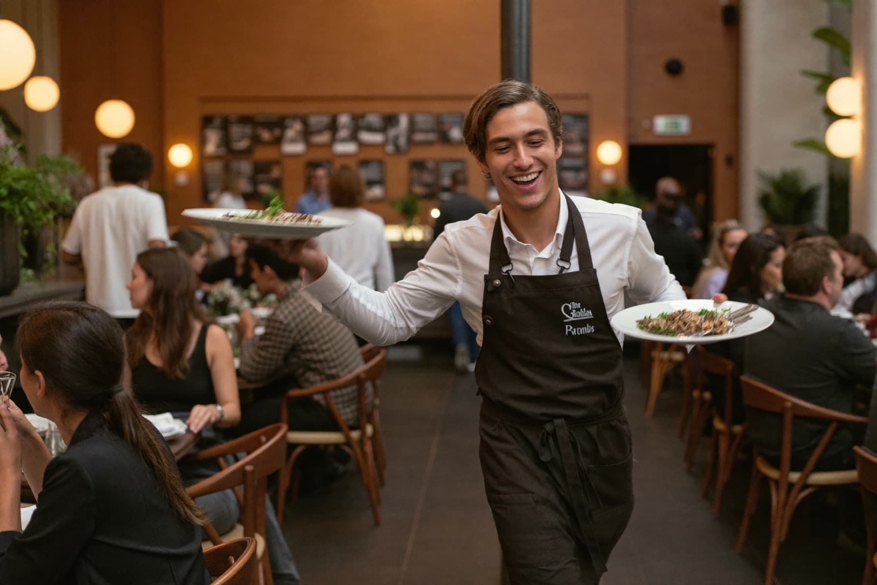 Smiling waiter carrying plates through a warm restaurant
